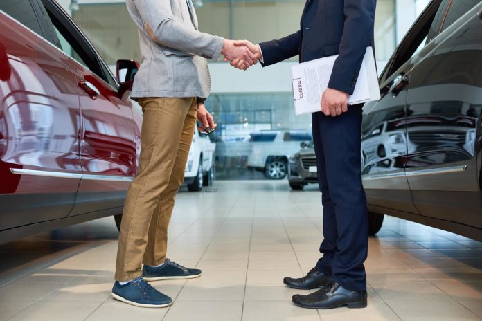 people-shaking-hands-in-car-showroom-6NXFKM8